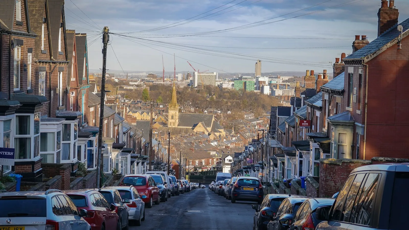 A terraced street with cars parked at the kerb and no driveways